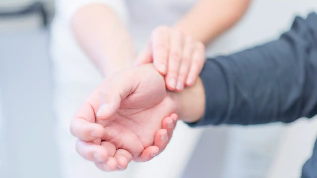 Hand fühlt Puls an Handgelenk